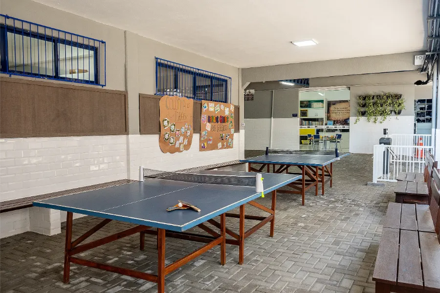 Área de lazer coberta com mesas de tênis de mesa no Colégio Atlântico, espaço voltado à recreação e socialização dos estudantes.
