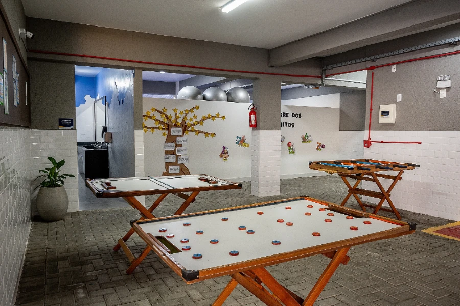 Espaço interno do Colégio Atlântico com mesas de jogos e decoração educativa, ambiente de lazer e integração entre os alunos.